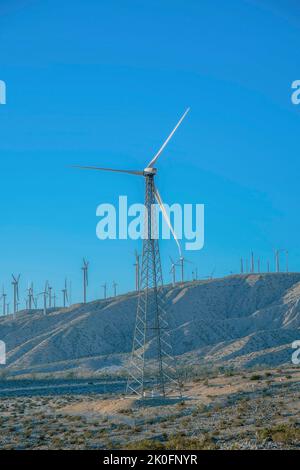 Moulin à vent avec tour de treillis sur une ferme de moulin à vent dans un désert en Californie. Éolienne contre la vue des moulins à vent sur une chaîne de montagne contre le b Banque D'Images