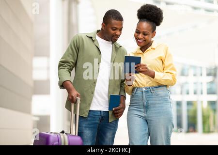 Couple afro-américain joyeux portant un passeport à l'intérieur de l'aéroport Banque D'Images