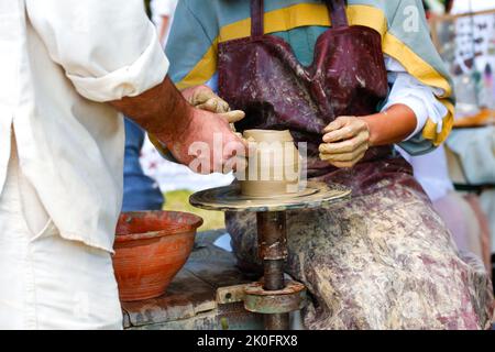 Defocus Woman potter enseignant l'art de la fabrication de pot. Femmes travaillant sur la roue de potiers faisant des objets d'argile dans l'atelier de poterie. Classe principale sur la modélisation Banque D'Images