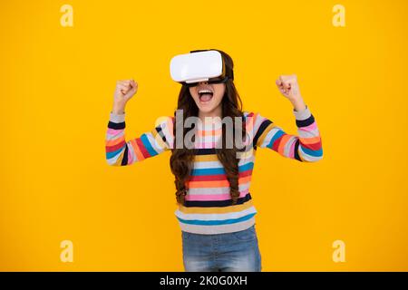 Adolescent stupéfié. Gadgets virtuels pour enfant, temps libre et étude. La jeune fille de l'école utilise des lunettes vr, isolées sur fond jaune, prise de vue en studio. Excitée Banque D'Images