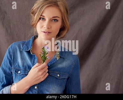 La vraie beauté vient de l'intérieur. Portrait d'une belle jeune femme tenant des fleurs coupées. Banque D'Images