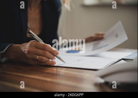 Vue d'angle bas d'un conseiller financier regardant à travers un rapport statistique d'entreprise avec des graphiques et des graphiques. Banque D'Images