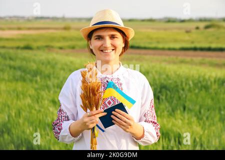 Recentrer le portrait de la jeune femme ukrainienne. Bouquet d'épillets dorés mûrs de blé attachés sur le fond de la nature du pré. Montrant le drapeau de l'Ukraine. Sourire Banque D'Images