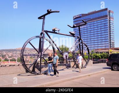 Tbilissi, Géorgie - 07 23 2022: Personnes marchant devant le monument de Big Bicycle sur la place de la Révolution rose en face de l'hôtel Radisson Blu Iveria, Tbilissi Banque D'Images