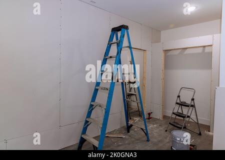 Un panneau de plâtre est en cours d'installation dans une nouvelle pièce d'accueil. La cloison sèche est prête à être fixée dans la pièce Banque D'Images