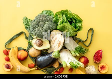 Légumes et fruits verts frais dans un sac à ficelle verte sur fond jaune. Banque D'Images