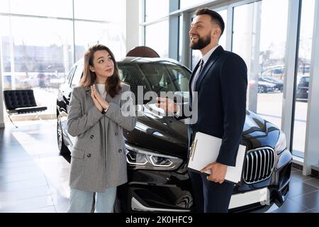 employé de la concession automobile parlant du nouveau modèle de voiture à l'acheteur femme, le concept d'acheter une voiture à la location Banque D'Images