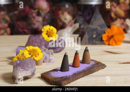 Cônes d'Encens sur dalle de pierre avec cristaux de roche et fleurs Banque D'Images