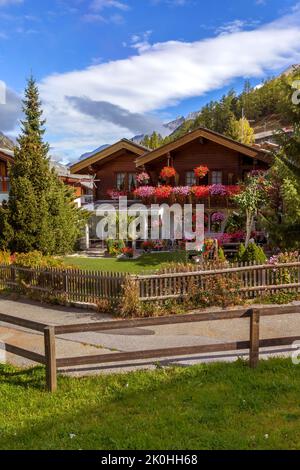 Chalet alpin traditionnel en bois avec fleurs de géranium sur la fenêtre en été, village alpin de Zermatt, Suisse, Alpes suisses Banque D'Images