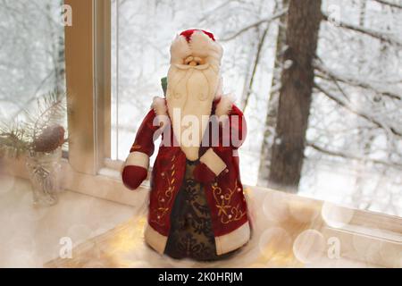 Le Père Noël en fourrure rouge sur fond de paysage enneigé d'hiver dans une fenêtre ouverte a volé pour féliciter le nouvel an et Noël pour un fes Banque D'Images