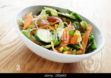 Faire frire les légumes crus dans un bol blanc sur une table en bois Banque D'Images