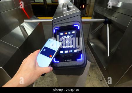 Un smartphone avec Google Wallet prend un tourniquet de métro New York équipé d'un lecteur de paiement sans contact OMNY acceptant les paiements NFC Banque D'Images