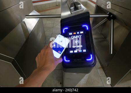 Un smartphone avec Google Wallet prend un tourniquet de métro New York équipé d'un lecteur de paiement sans contact OMNY acceptant les paiements NFC Banque D'Images