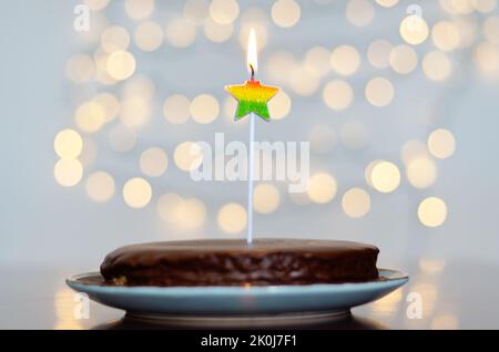 Gâteau d'anniversaire festif avec bougies et décoration de carnaval colorée sur fond de bokeh lumineux. Carte de vœux. Fête et fête Banque D'Images