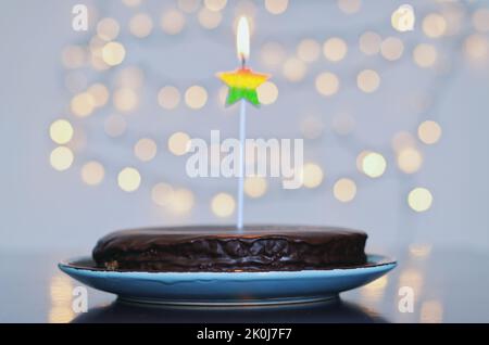 Gâteau d'anniversaire festif avec bougies et décoration de carnaval colorée sur fond de bokeh lumineux. Carte de vœux. Fête et fête Banque D'Images