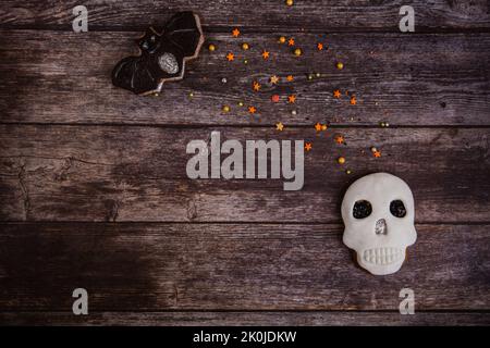 Biscuit de pain d'épice peint à la main crâne d'Halloween effrayant avec des saupoudrés de couleur sur fond de bois. Vue de dessus. Pose à plat. Copier l'espace Banque D'Images