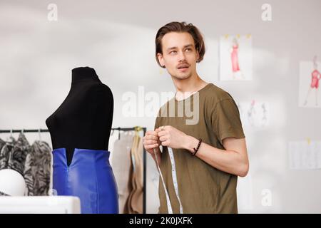 Portrait d'un jeune couturier sur le fond d'un mannequin et d'une machine à coudre Banque D'Images