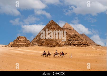 Le Caire, Égypte. 08.25.2022. Groupe de touristes à cheval chameaux voyant les pyramides de Menkaure, Chephren et Cheops. Banque D'Images