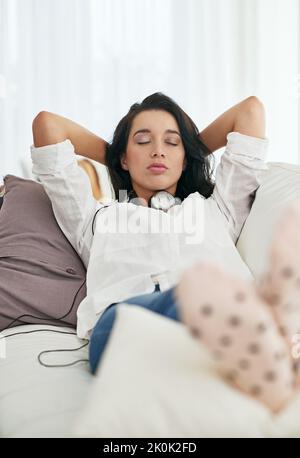 Rien n'est plus unique... rester à la maison pour un vrai confort. Une jeune femme prend une sieste sur son canapé à la maison. Banque D'Images