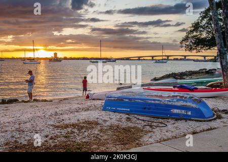 Sarasota, FL, US-30 mai 2022 : silhouette de père et de fils pêchant au coucher du soleil avec de vieux bateaux sur la plage avec un ciel spectaculaire Banque D'Images