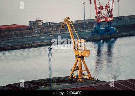Vue aérienne de l'extraction industrielle du charbon avec des machines de travail et des piles de matériaux sur la côte brumeuse Banque D'Images