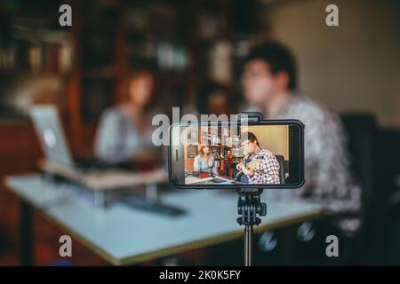 Musicien masculin avec guitare contre chant chanteur chant sur téléphone portable pendant le processus d'enregistrement dans la maison Banque D'Images