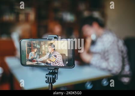 Musicien masculin avec guitare contre chant chanteur chant sur téléphone portable pendant le processus d'enregistrement dans la maison Banque D'Images