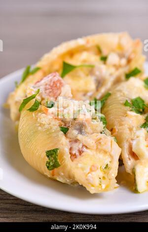 Pâtes Conchiglie farcies de morceaux de poulet tendres, de champignons et de légumes dans une riche sauce crémeuse. Banque D'Images