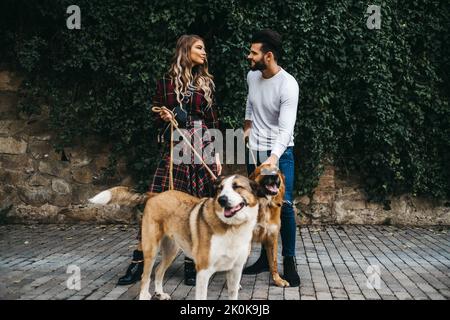 Jeune couple attrayant marchant leurs chiens sur une laisse dans les rues de Barcelone, Espagne Banque D'Images