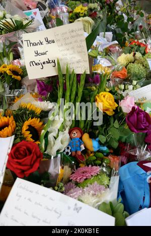 Des bouquets , des hommages écrits, des jouets en peluche, des bougies et des cartes ont été posés en l'honneur de la Reine Elizabeth à Green Park et des milliers de personnes ont continué à affluer à la résidence royale Buckingham Palace dans le centre de Londres. Banque D'Images