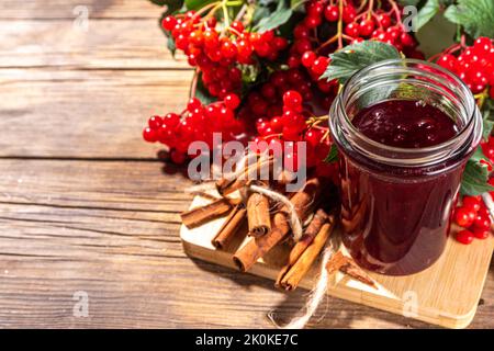 Recette de confiture d'automne, conservation et saison de récolte. Confiture rouge maison de baies de viburnum bio, avec baies fraîches sur brindilles et cannelle Banque D'Images