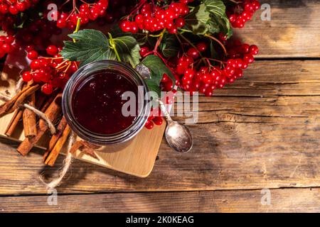 Recette de confiture d'automne, conservation et saison de récolte. Confiture rouge maison de baies de viburnum bio, avec baies fraîches sur brindilles et cannelle Banque D'Images