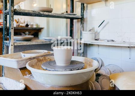 Pot d'argile laissé sur la roue de poterie après le processus de mise en forme dans l'atelier d'artisanat créatif Banque D'Images