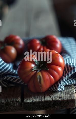Du dessus des tomates rouges mûres avec une serviette rayée sur une table en bois Banque D'Images