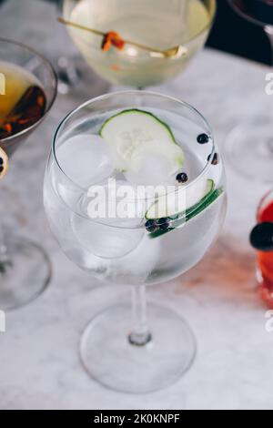 Verre de gin tonique à l'alcool rafraîchissant avec tranches de concombre et glaçons sur la table Banque D'Images