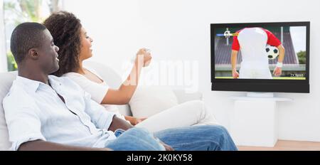 Couple afro-américain assis sur le canapé et regardant un match de football Banque D'Images