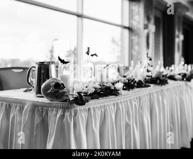 Une photo en niveaux de gris d'une table de mariage décorée sur le thème de l'Halloween Banque D'Images