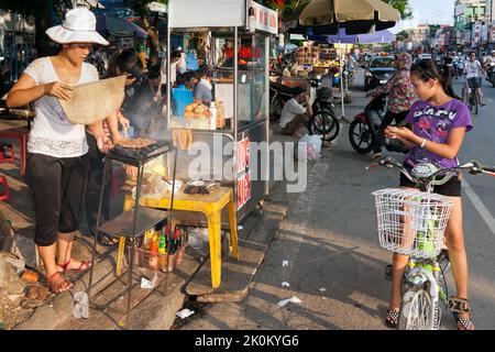 Vendeur vietnamien cuisinant sur barbecue dans le marché de rue en plein air, Hai Phong, Vietnam Banque D'Images