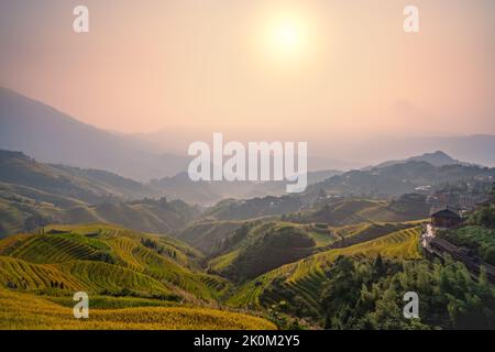 Longji Rice Terraces spectaculaire HDR coucher de soleil avec soleil incandescent sur les crêtes de montagne, Longsheng, Guilin, Guangxi, Chine Banque D'Images