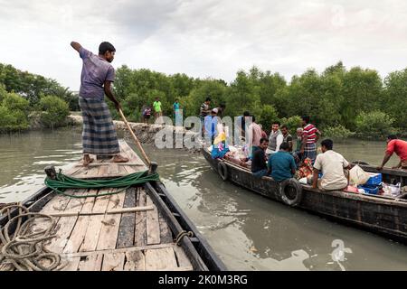 Transport de passagers sur des bateaux de l'autre côté de la rivière près de Shyamnagar. Les habitants des petites colonies le long des rivières du sud du Bangladesh ressentent clairement les effets du changement climatique. Le niveau de la mer monte et des barrages sont détruits. En conséquence, les champs et les importants étangs d'eau douce sont inondés et salés. Par conséquent, de grands efforts sont faits pour fortifier les banques. Des bâtiments résidentiels sont également élevés et fortifiés. Les projets de récolte d'eau de Suesswater sont très importants pour fournir aux gens de l'eau potable propre. Banque D'Images