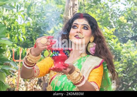 Les femmes mariées exécutant dhunuchi danse à l'occasion de Durga Agomoni comme rituel, la fumée sainte a couvert toute la zone. Banque D'Images