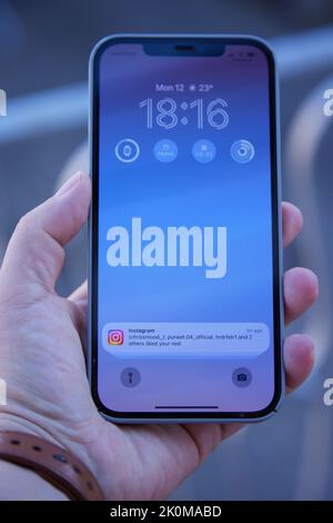 Apple iPhone 12 Pro Max dans la main avec ios 16 et notification instagram sur l'écran principal Banque D'Images