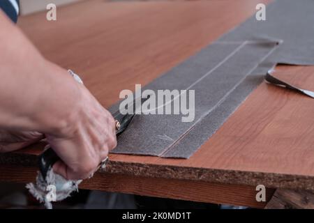 Un couteau coupe le tissu avec des ciseaux dans un atelier de couture Banque D'Images