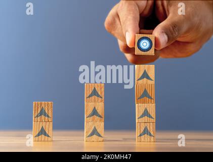 Photo en gros plan de blocs de bois empilés avec icône de cible comme symbole de la définition de nouveaux objectifs et de l'atteinte des cibles. Banque D'Images