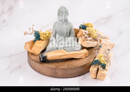 Brûlure d'Encens. Taches de bâtonnets de palo santo décorés d'herbes sèches et statue de Bouddha sur une table en marbre blanc. Rituel de fumigation de chambre pour meditati Banque D'Images