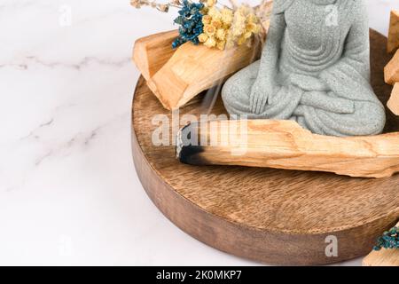 Des taches avec des bâtonnets de palo santo et la statue de Bouddha sur une table en marbre blanc. Rituel de fumigation en salle pour la méditation et les pratiques spirituelles. Burnin d'Encens Banque D'Images