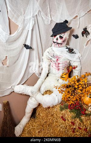 Squelette fait à partir de bandages pour la décoration d'Halloween est assis sur une balle de foin Banque D'Images