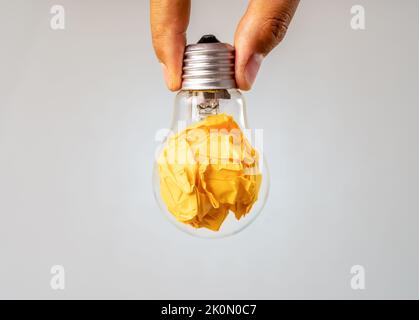 Gros plan photo de papier coloré émietté et ampoule dans le même cadre qu'un symbole de résistance, de persévérance et de travail acharné. Banque D'Images