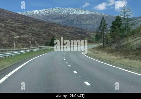 Route sinueuse vide dans les montagnes écossaises avec de la neige au loin Banque D'Images