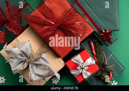 Boîtes-cadeaux en papier rouge et artisanal sur fond vert. Le concept de vacances, emballage écologique, achats en ligne pour Noël, nouvel an, Saint-Valentin, Fête des mères. Pose à plat. Banque D'Images